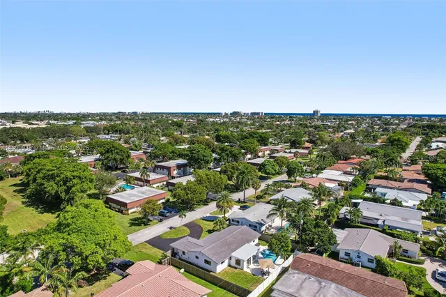 an aerial view of residential houses with outdoor space and trees