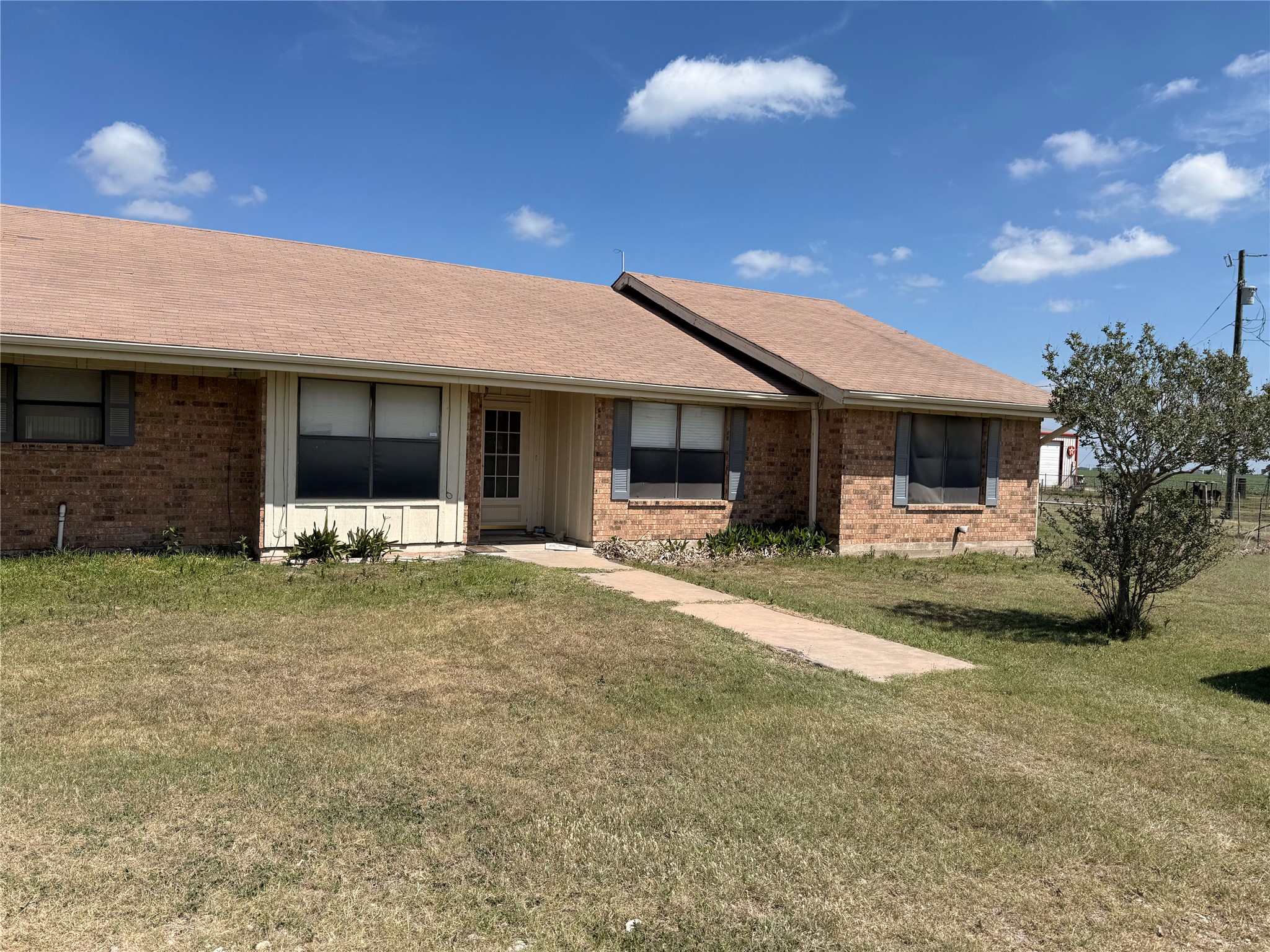 View of front of home with brick siding, roof with shingles, and a front yard