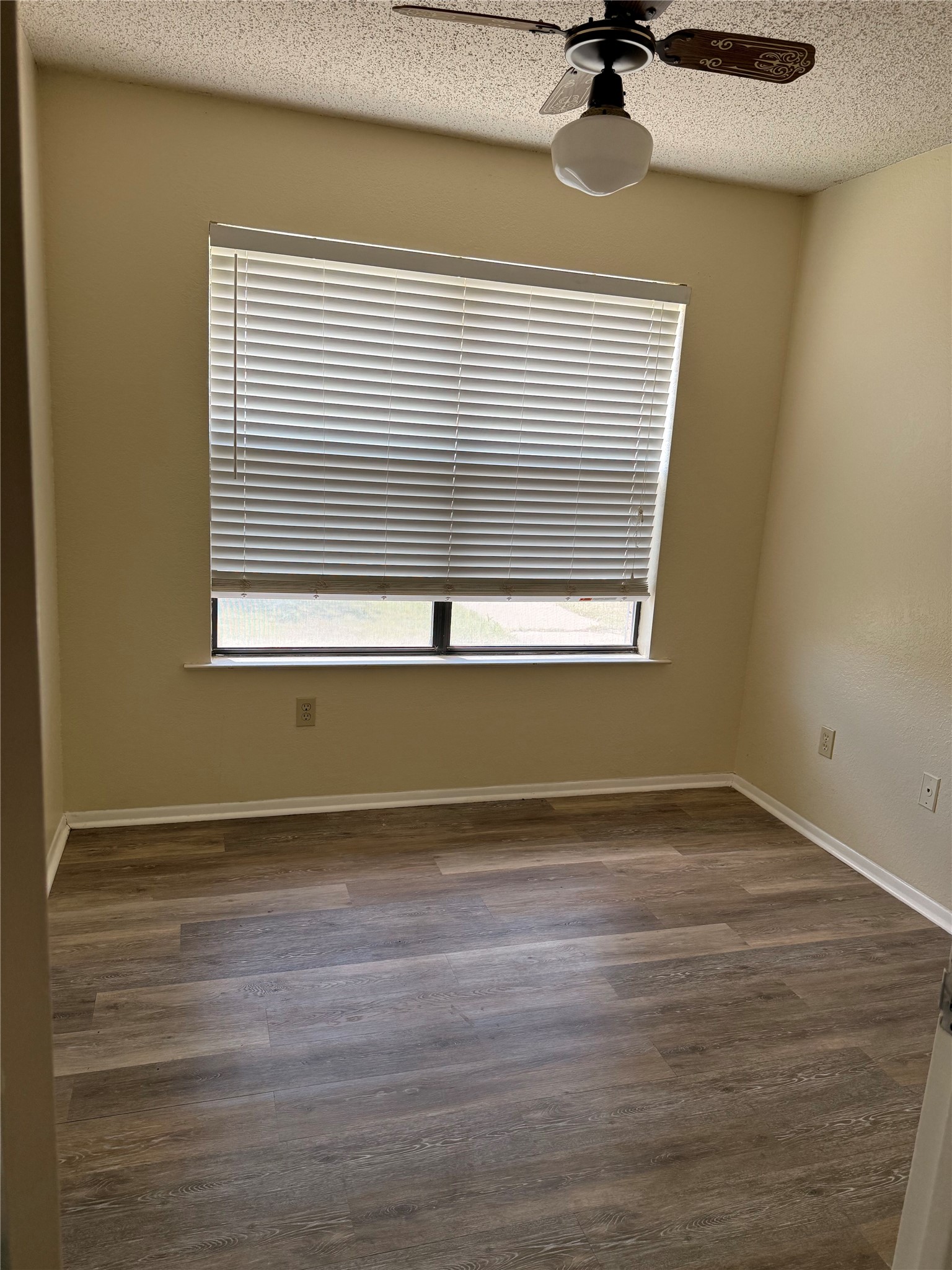 5931 Limmer Loop Hutto, TX 78634 - Photo 11 of 22 Empty room featuring a textured ceiling, a ceiling fan, and dark wood finished floors