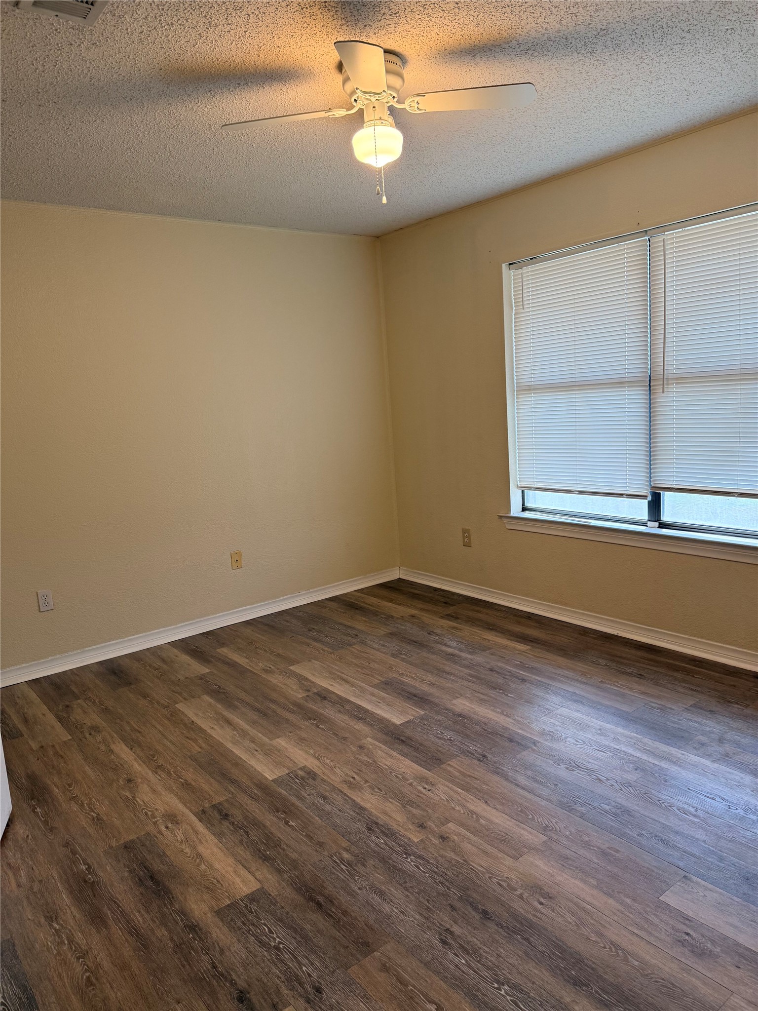 5931 Limmer Loop Hutto, TX 78634 - Photo 13 of 22 Spare room featuring dark wood-type flooring, a textured ceiling, and a ceiling fan