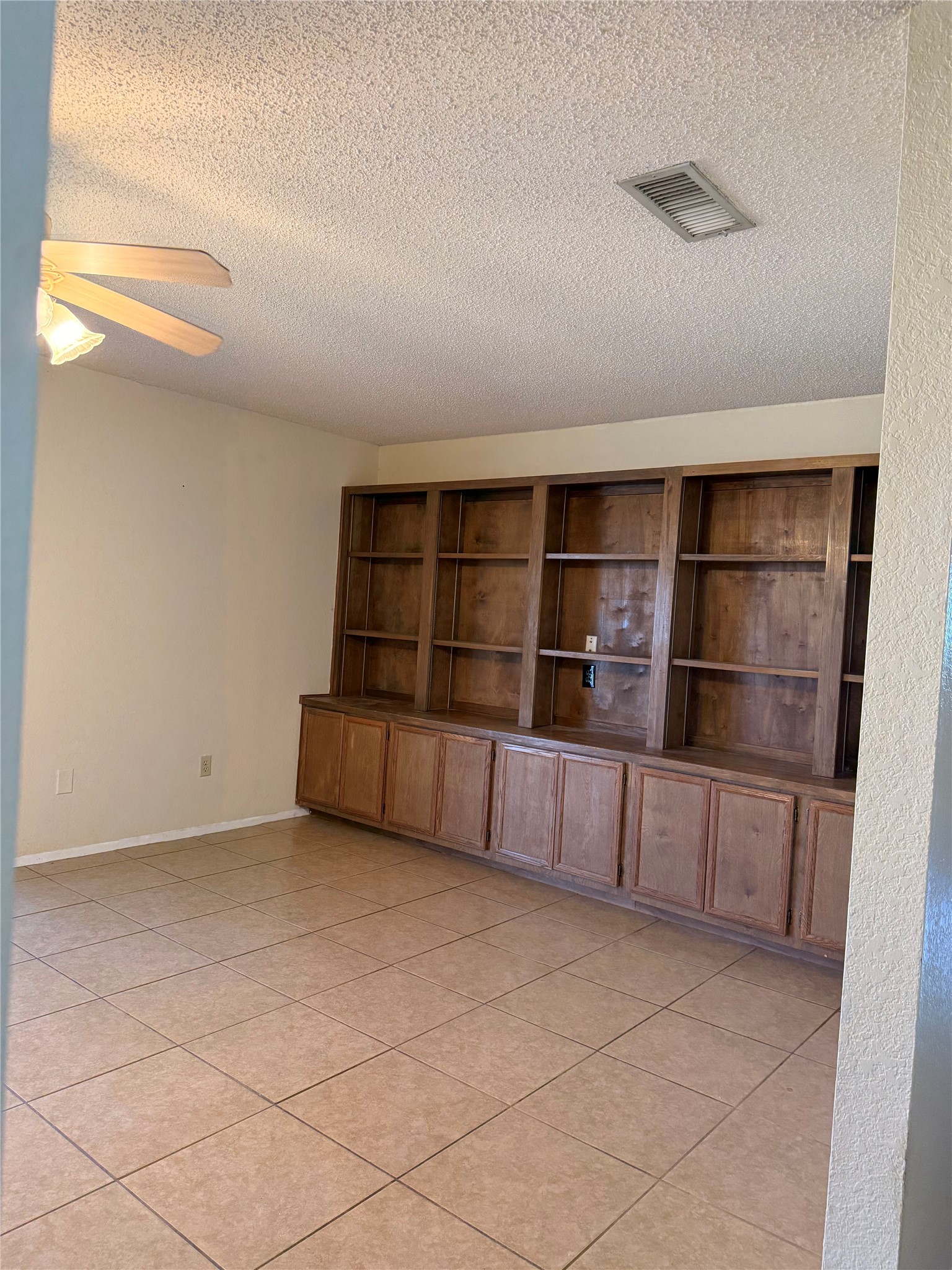 5931 Limmer Loop Hutto, TX 78634 - Photo 7 of 22 Empty room with a textured ceiling, light tile patterned floors, and ceiling fan