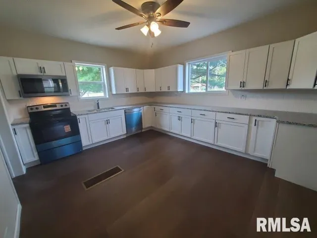 a kitchen with granite countertop a stove a sink a window and dining table