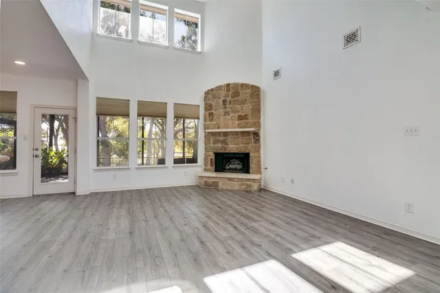 an empty room with wooden floor a fireplace and windows
