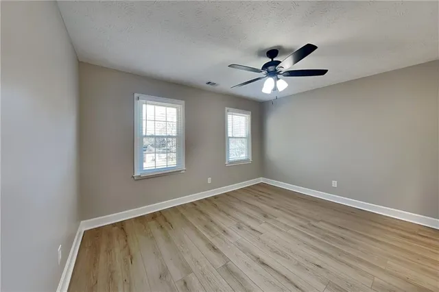a view of an empty room with window and wooden floor