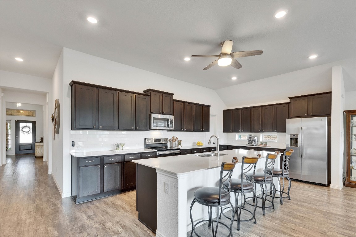 1312 Terrace View Drive Georgetown, TX 78628 - Photo 3 of 40 Kitchen featuring appliances with stainless steel finishes, light wood-type flooring, vaulted ceiling, a kitchen breakfast bar, and recessed lighting