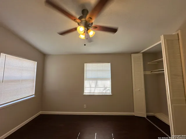 an empty room with windows and chandelier fan