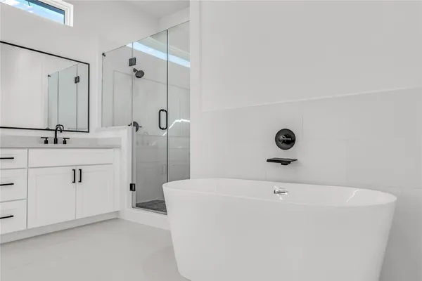 a bathroom with a tub sink vanity and mirror