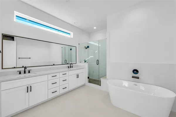 a bathroom with double vanity sink a mirror and a bathtub