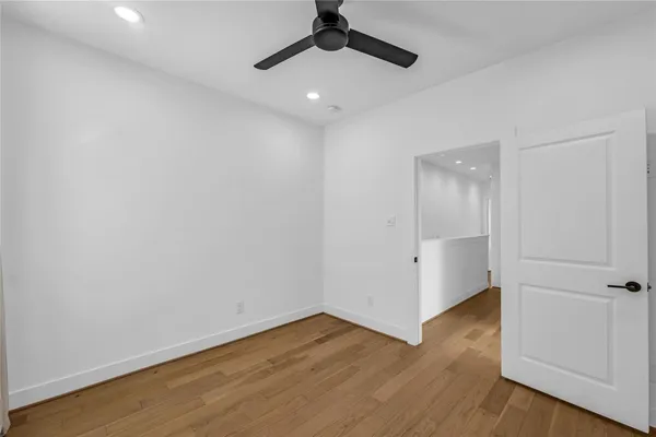an empty room with wooden floor and ceiling fan