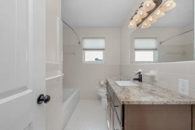 a bathroom with a granite countertop sink a mirror and a shower