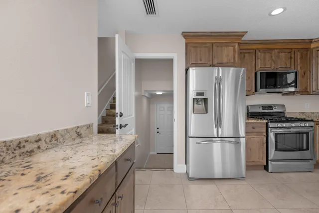 a kitchen with granite countertop a refrigerator and a stove top oven