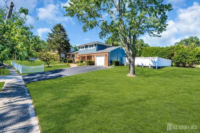 a view of a house with a big yard and large trees