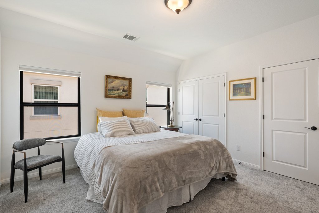 1221 Siena Sunset Road Leander, TX 78641 - Photo 29 of 39 Carpeted bedroom featuring multiple windows with roller shades, a ceiling-mounted light fixture, and two panel doors with black hardware