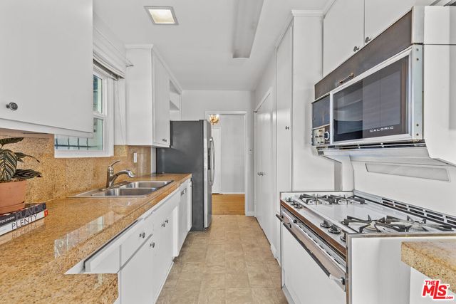 a kitchen with stainless steel appliances granite countertop a sink stove refrigerator and cabinets