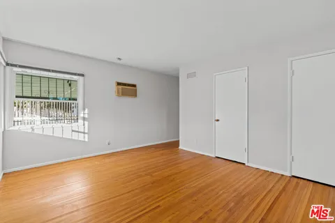 a view of an empty room with wooden floor and a window