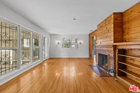 a view of an empty room with a fireplace and wooden floor