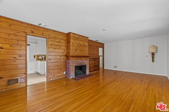 a view of empty room with wooden floor and fireplace