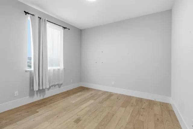 an empty room with wooden floor and a window