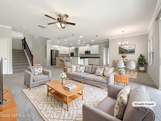 a living room with furniture kitchen view and a chandelier