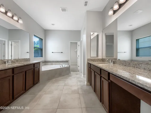 a bathroom with a granite countertop double vanity sink and a mirror