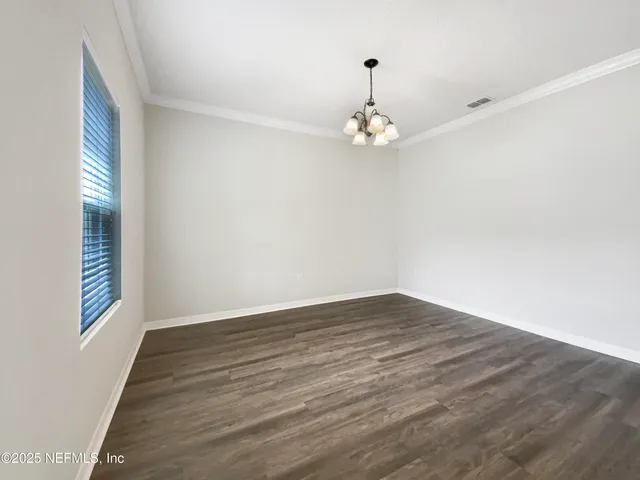a view of empty room with wooden floor and window