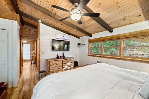 a bedroom with a large bed and a flat tv screen on dresser