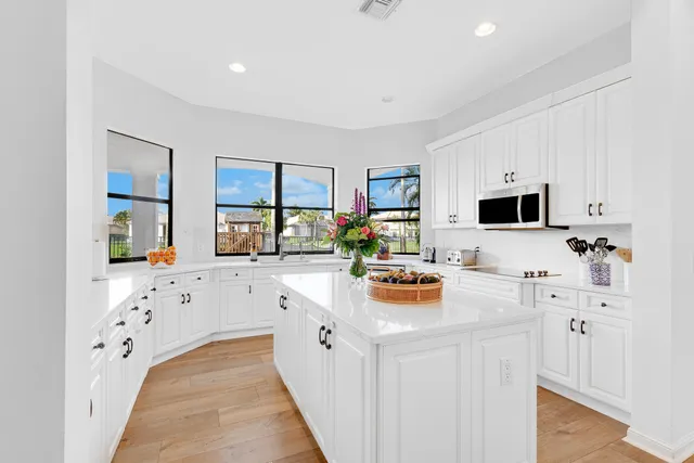 a white kitchen with stainless steel appliances a stove a sink a refrigerator a white counter tops and white cabinets