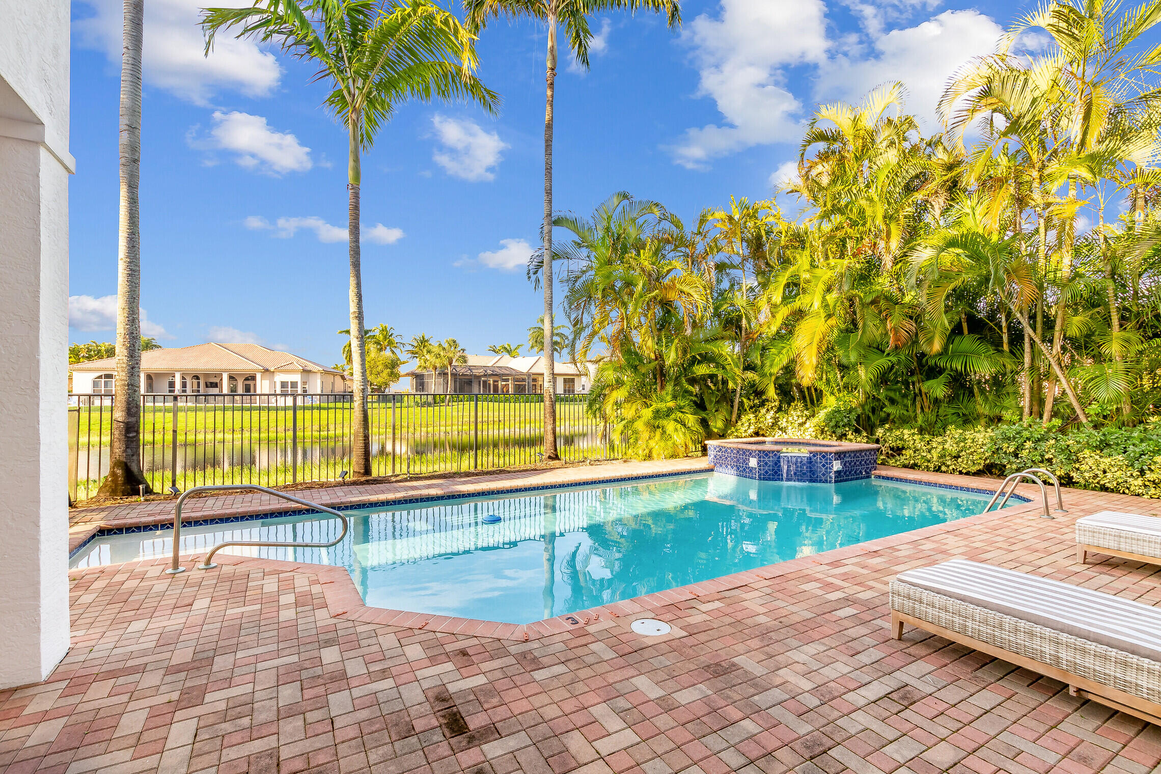 11663 Sunrise View Lane Wellington, FL 33449 - Photo 38 of 43 a view of a swimming pool with lawn chairs under an umbrella