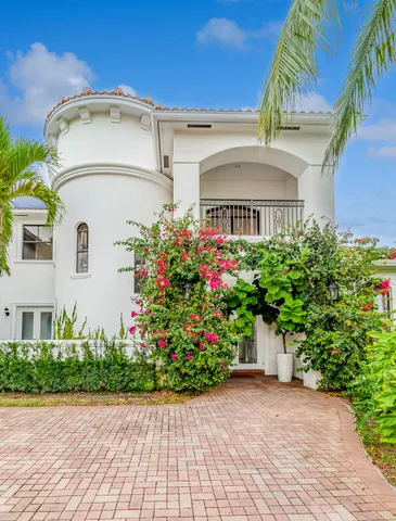a view of a white house with a flower garden and a chair