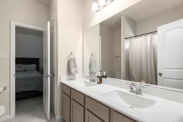 a en suite bathroom with a double vanity sink and a mirror