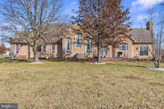 a front view of a house with a yard covered with trees