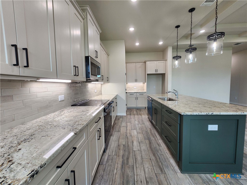 406 Talon Loop Salado, TX 76571 - Photo 9 of 31 a kitchen with stainless steel appliances granite countertop a sink a stove and a wooden floors