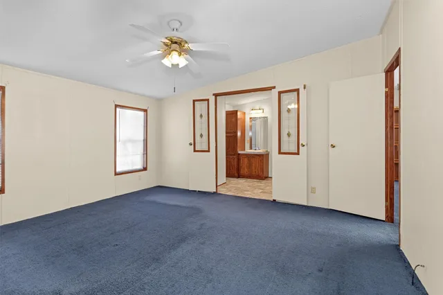 an empty room with windows and chandelier fan
