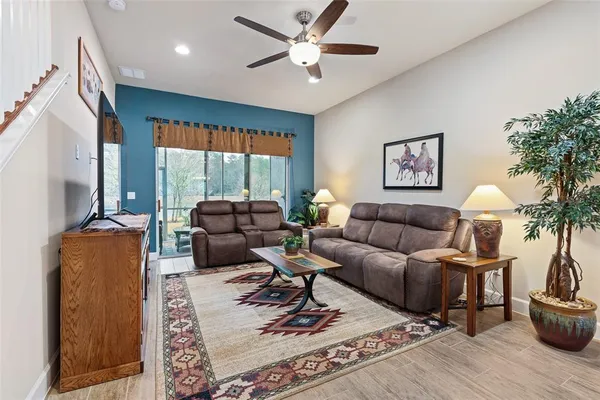 a living room with furniture a rug potted plant and a large window