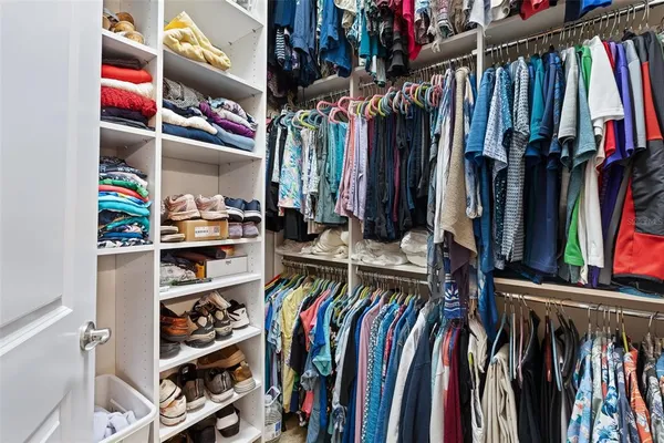 a view of walk in closet with clothes and shoes