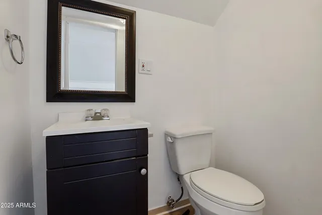 a bathroom with a toilet sink vanity and mirror