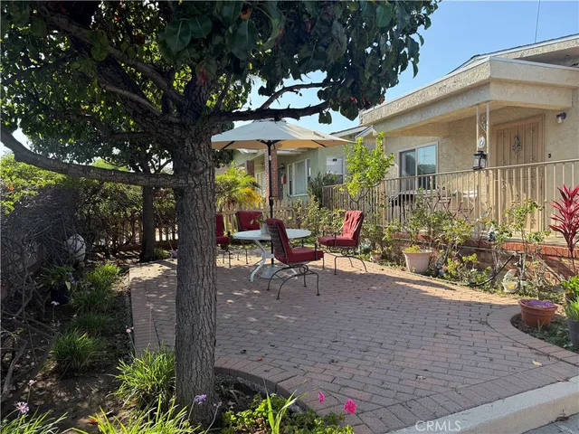 a view of a patio with table and chairs potted plants and large tree