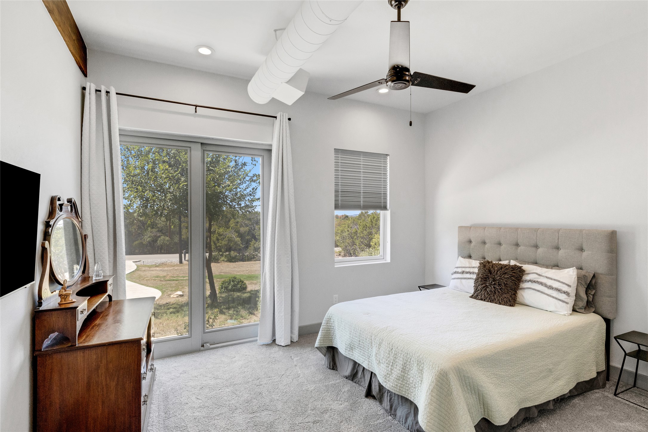 4227 Eck Lane Austin, TX 78734 - Photo 23 of 30 Bedroom featuring light colored carpet, access to exterior, multiple windows, and a ceiling fan