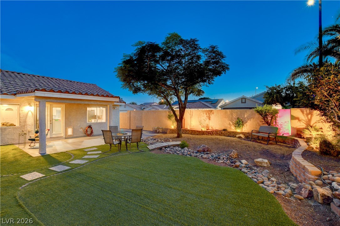 910 Cobblestone Cove Road North Las Vegas, NV 89081 - Photo 24 of 30 A private backyard oasis features artificial turf, vibrant lighting, and a charming covered patio.