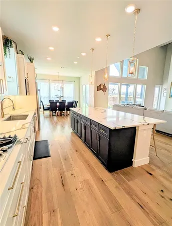 a large kitchen with stainless steel appliances kitchen island granite countertop a large counter top a stove and a wooden floors