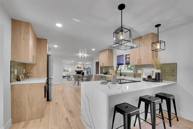 a kitchen with stainless steel appliances a dining table chairs and stove