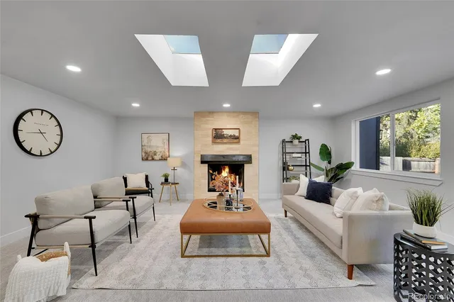 a living room with furniture a clock on wall and a large window