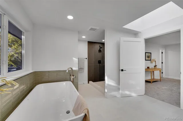 a bathroom with a tub a sink and a large mirror