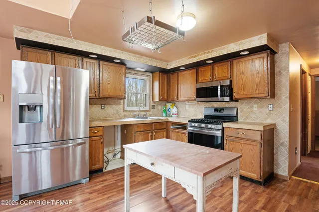 a kitchen with a refrigerator a sink dishwasher and a stove with wooden floor