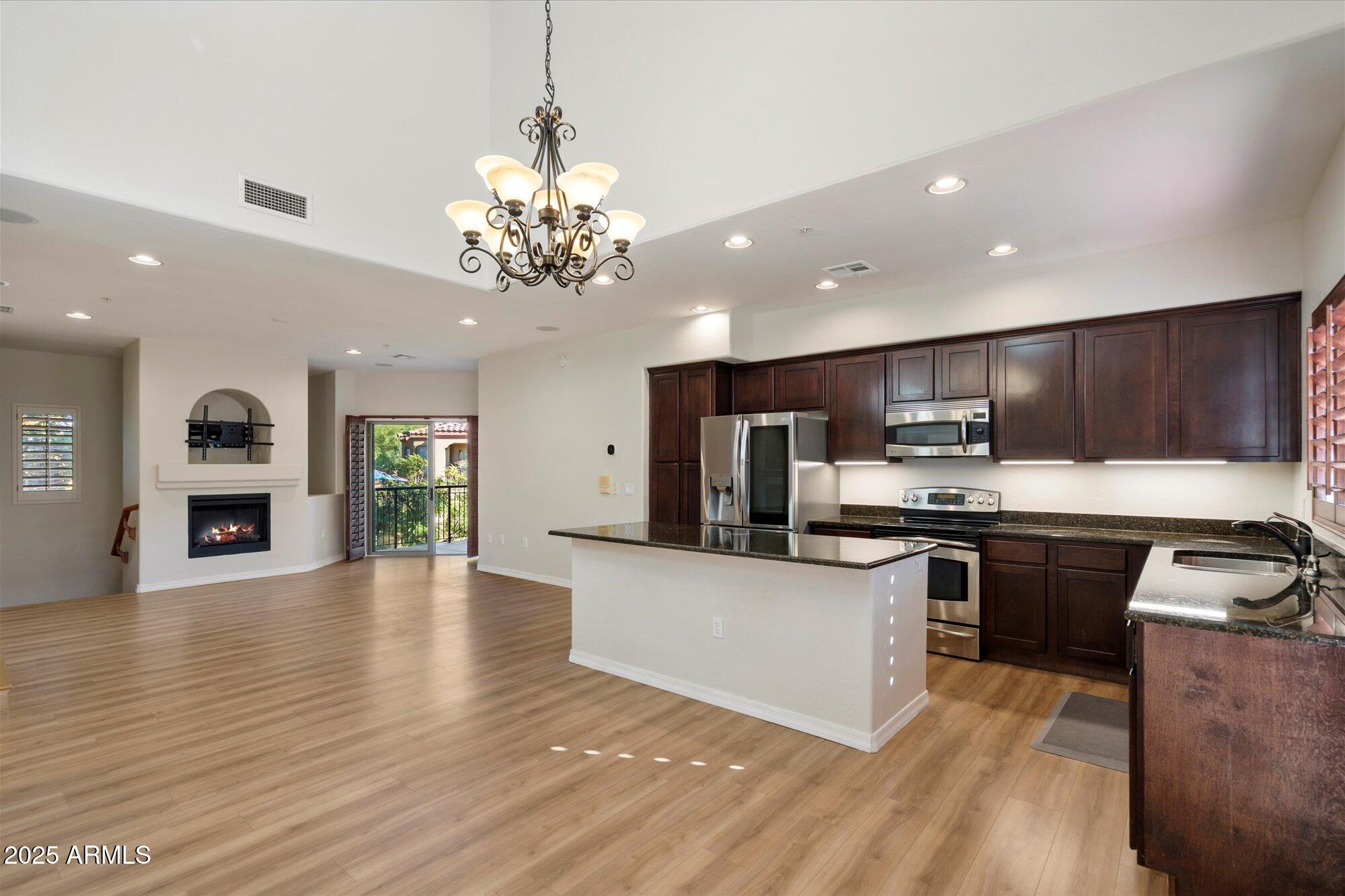 a large kitchen with stainless steel appliances granite countertop a stove top oven a sink dishwasher with chairs and wooden floor