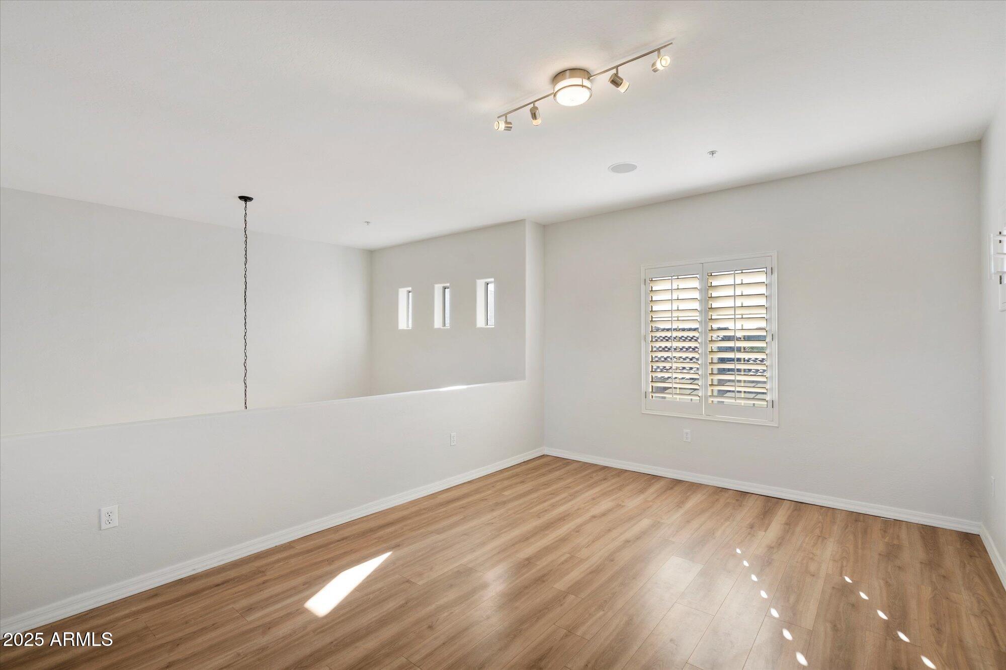 3935 East Rough Rider Road, Unit 1034 Phoenix, AZ 85050 - Photo 15 of 22 a view of an empty room with wooden floor and a window