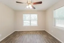 an empty room with a window and a fan