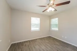 an empty room with a window and a fan