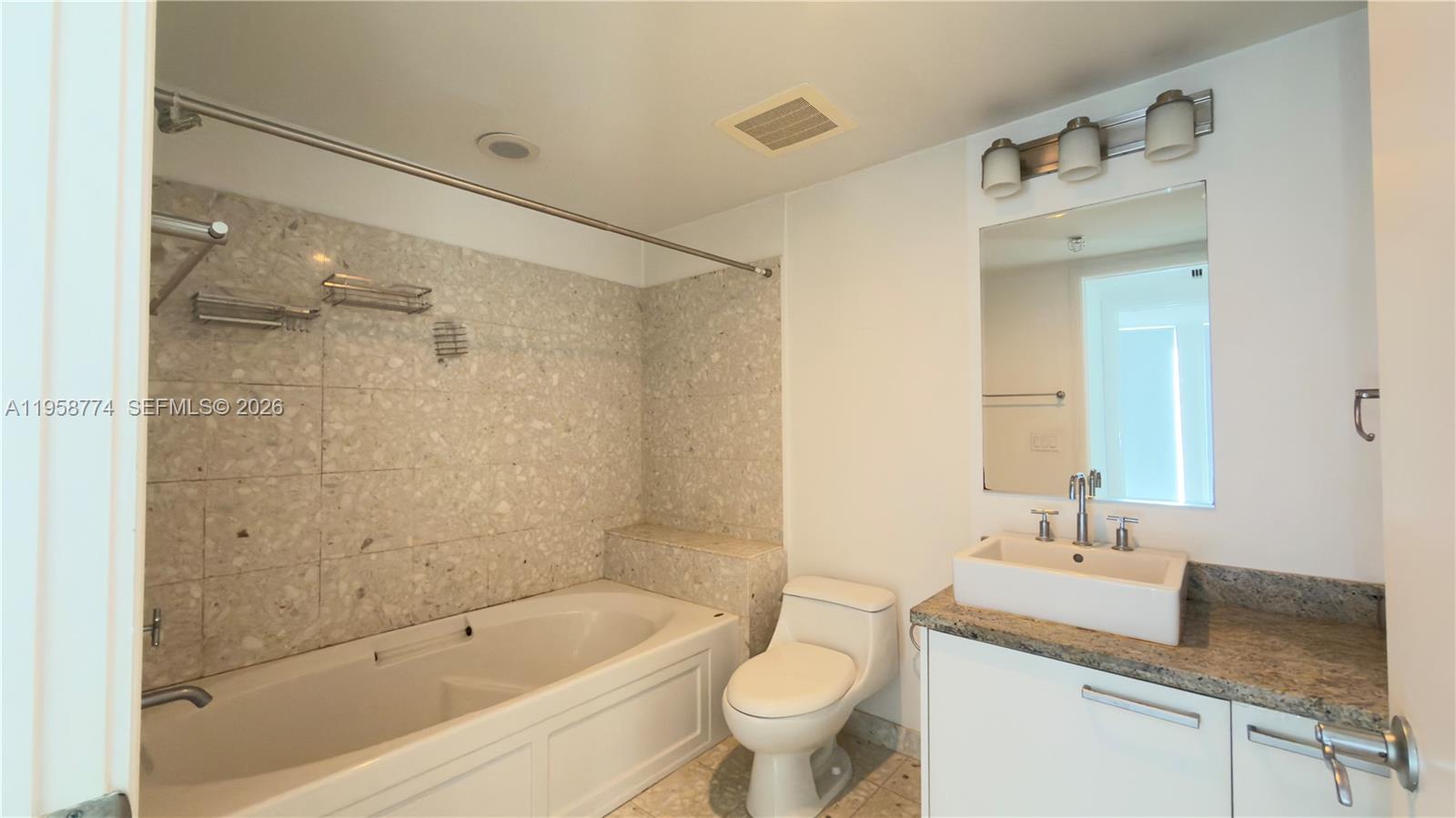 185 Southwest 7th Street, Unit 3810 Miami, FL 33130 - Photo 16 of 29 a bathroom with a granite countertop sink mirror toilet and bathtub