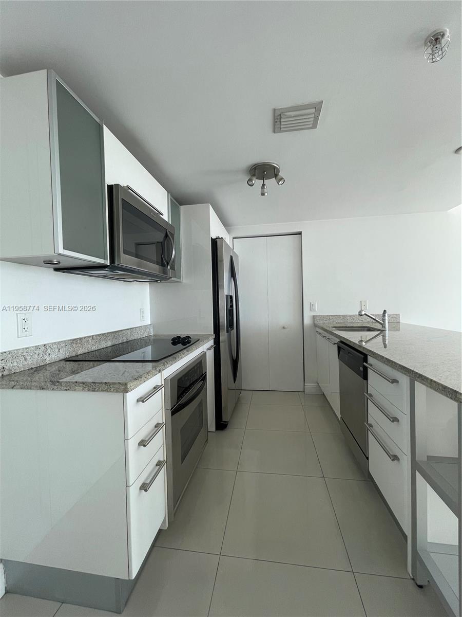 185 Southwest 7th Street, Unit 3810 Miami, FL 33130 - Photo 10 of 29 a kitchen with stainless steel appliances granite countertop a stove a sink and a microwave